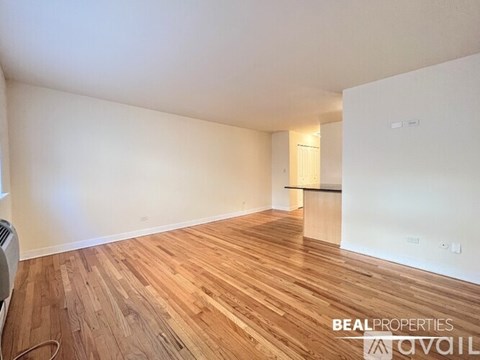 A room with wooden flooring and white walls, with a door on the right side.