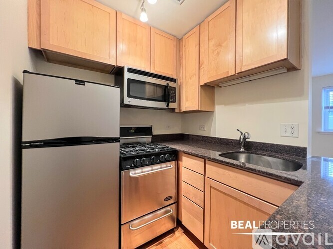 A kitchen with wooden cabinets and a black refrigerator.