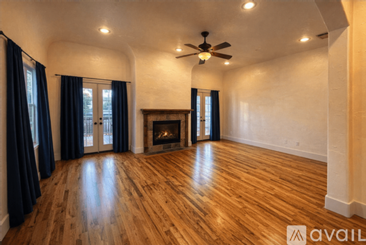 A spacious room with a fireplace and wood flooring.