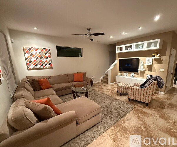 A living room with a large sectional sofa and a flat screen TV mounted on the wall.