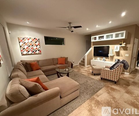 A living room with a large sectional sofa and a flat screen TV mounted on the wall.