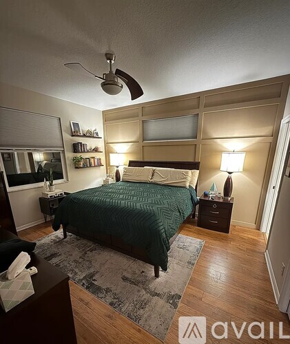 A bedroom with a bed, nightstand, and a ceiling fan.