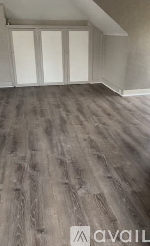 A room with wooden flooring and white cupboards.