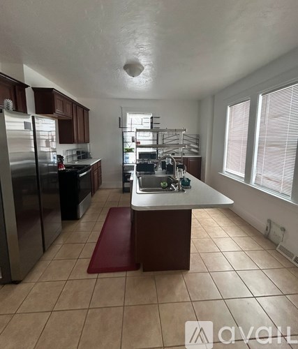 A kitchen with a refrigerator, sink, and cabinets.