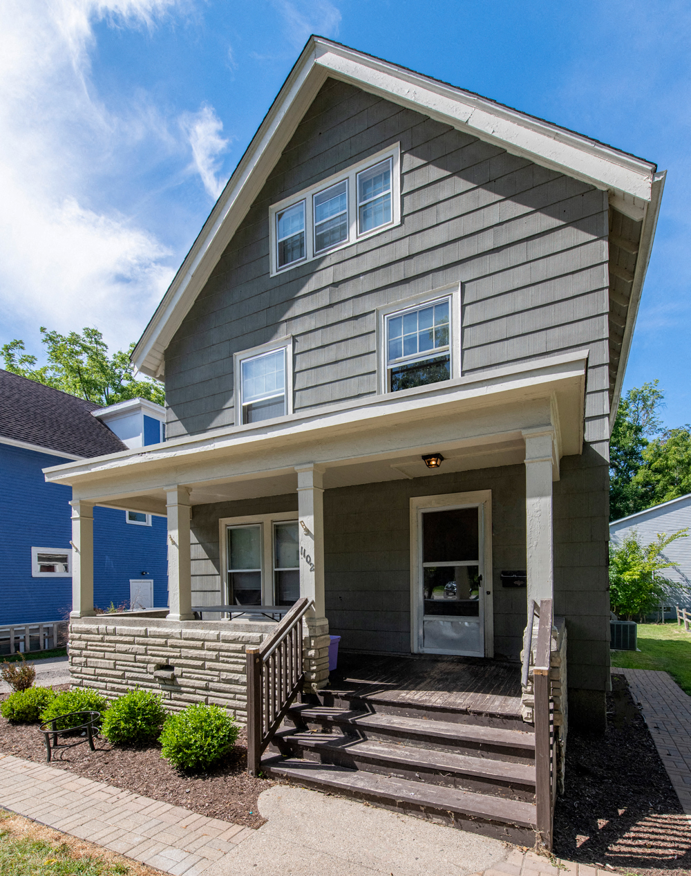 the front of a gray house with a front porch
