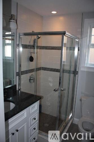 A bathroom with a glass shower stall and a toilet.