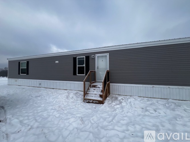A grey building with a door and windows is surrounded by snow.