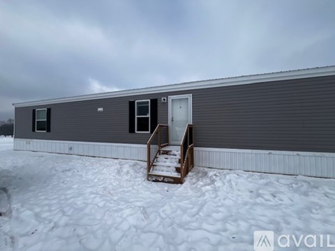 A grey building with a door and windows is surrounded by snow.