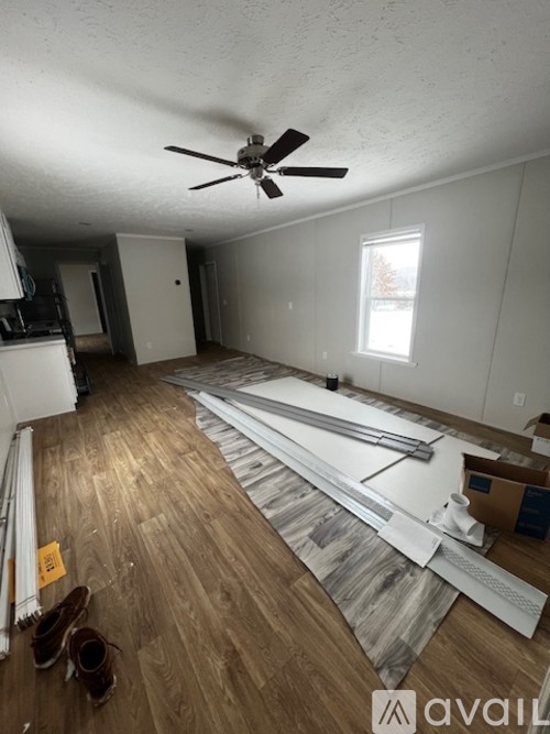 A room with wooden flooring and a ceiling fan is under renovation.