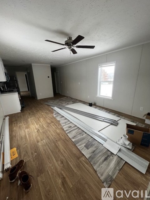 A room with wooden flooring and a ceiling fan is under renovation.