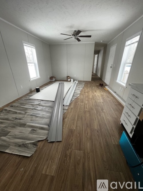 A room under construction with wooden flooring and a ceiling fan.
