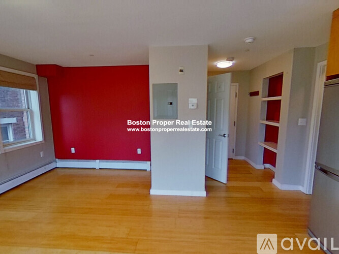 A room with wooden flooring and a red wall.