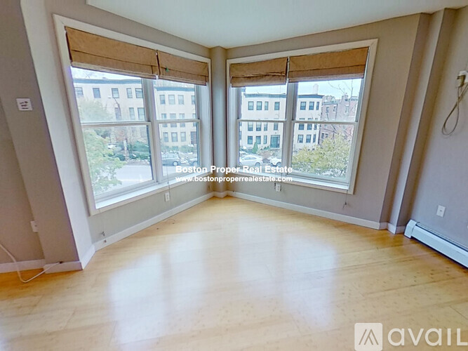 A room with wooden floors and large windows overlooking a city street.
