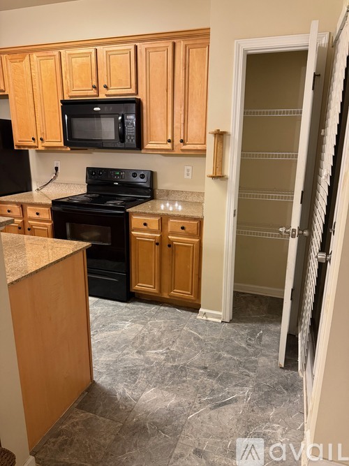 A kitchen with wooden cabinets and a black microwave above the stove.