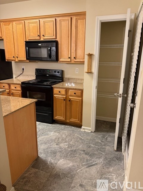 A kitchen with wooden cabinets and a black microwave above the stove.