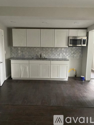 A kitchen with white cabinets and a grey backsplash.