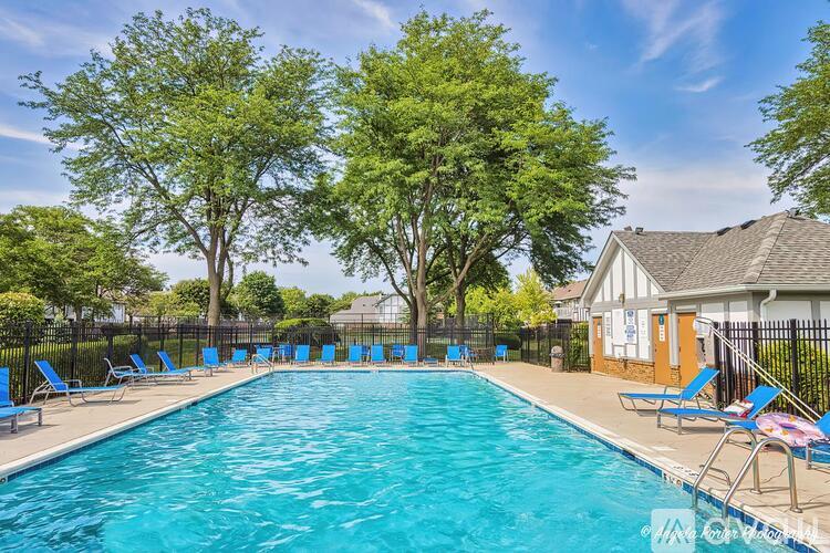 A swimming pool surrounded by trees and lounge chairs.