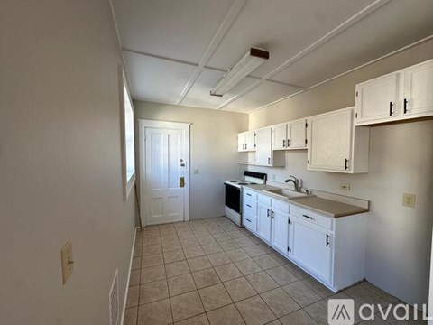 A kitchen with white cabinets and a tiled floor.