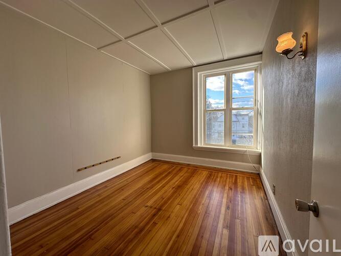 A room with wooden floors and a window letting in light.