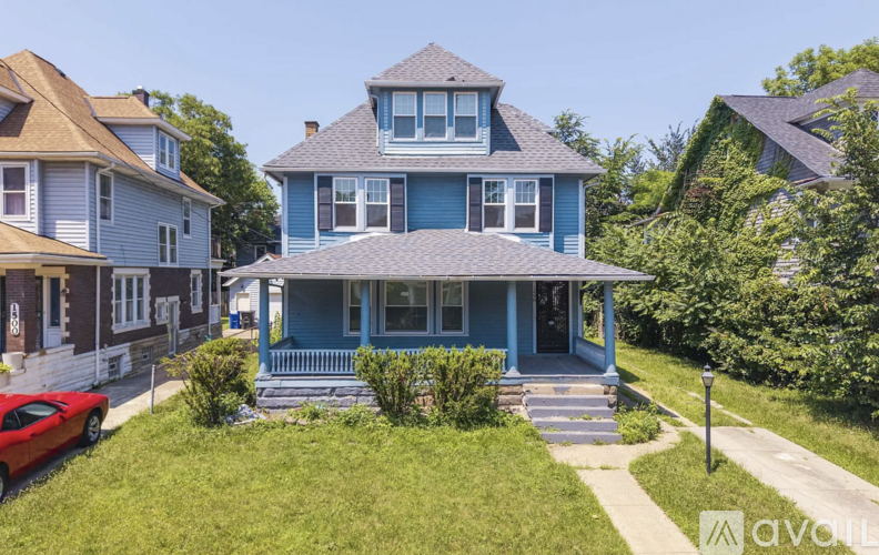 A blue house with a red car parked in front.