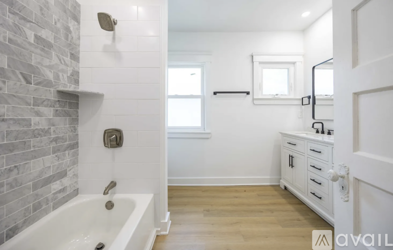 A white bathroom with a tub and a window.