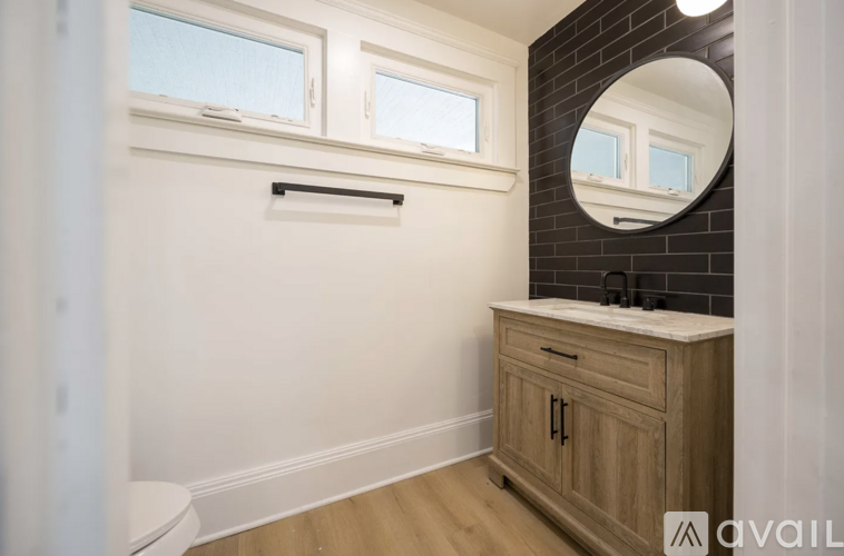 A bathroom with a wooden cabinet and a round mirror above it.