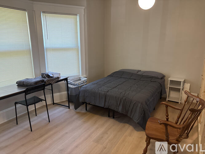 A bedroom with a bed, chair, and desk.