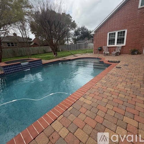 A brick patio leads to a rectangular pool.