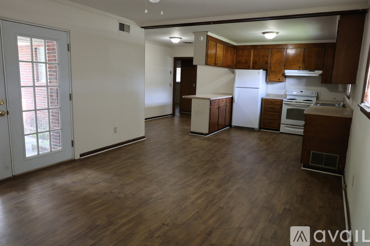 A spacious kitchen with wooden floors and white appliances.