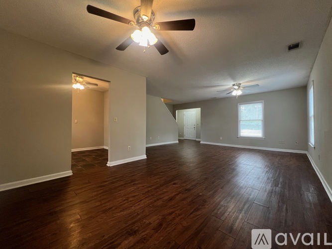 A spacious room with wooden floors and a ceiling fan.