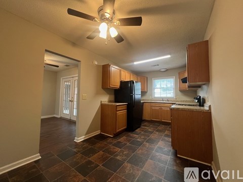 A kitchen with a black refrigerator and wooden cabinets.