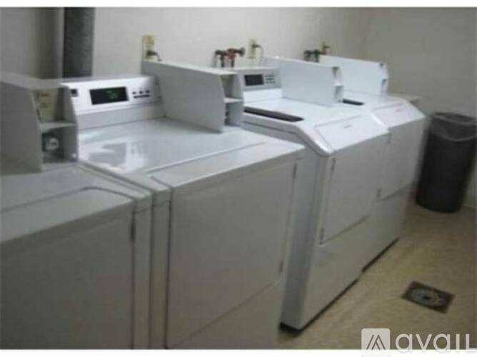 A row of white washing machines are lined up in a laundromat.