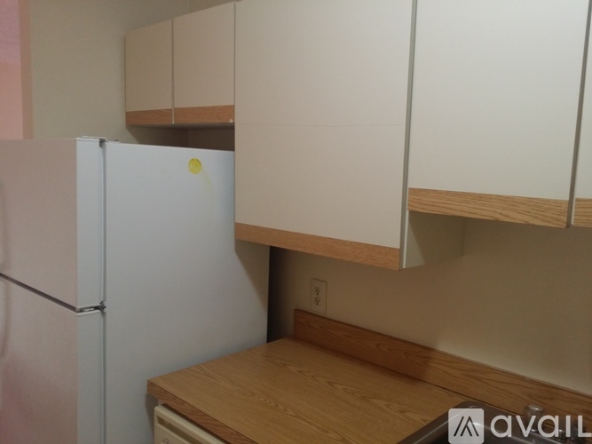 A white refrigerator in a kitchen with wooden cabinets.
