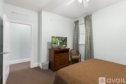 A bedroom with a bed, dresser, chair, and television.