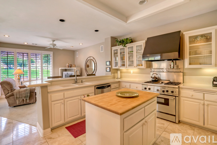 A kitchen with a wooden island in the middle and a fan on the ceiling.