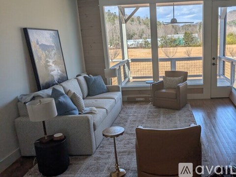 A living room with a grey couch, a brown chair, and a painting on the wall.