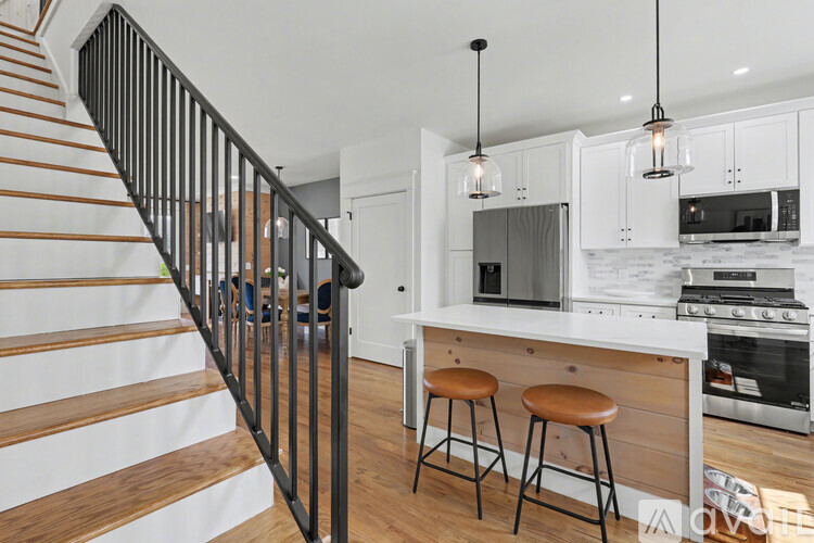 A modern kitchen with white cabinets and a black staircase.