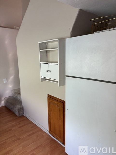 A kitchen with a white fridge and a wooden door.