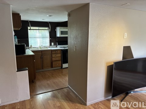 A kitchen with wooden floors and a TV on the right side.