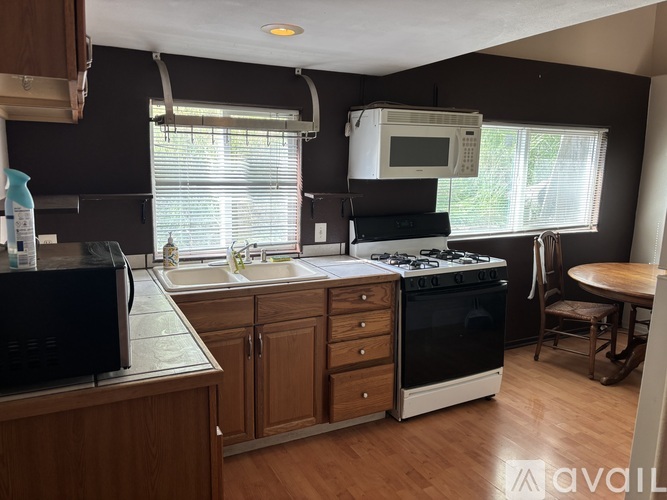 A kitchen with wooden cabinets and a black microwave.