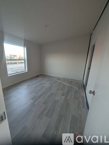 A room with grey flooring and a window overlooking a parking lot.