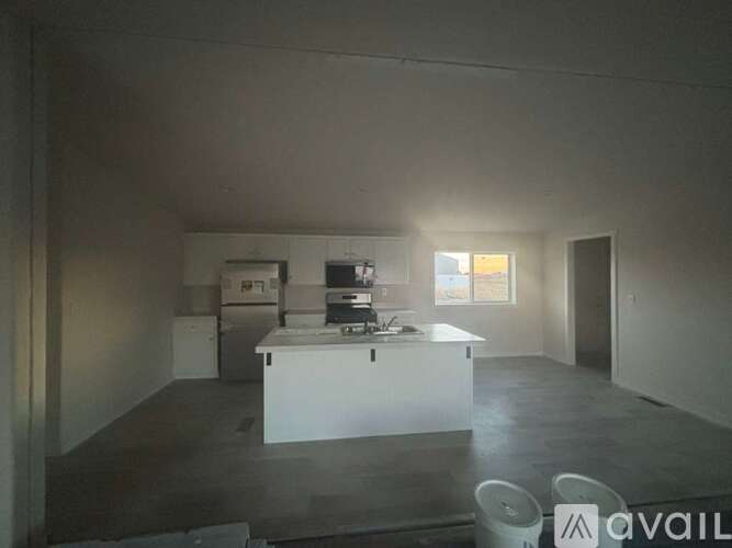 A room with a white counter and a fridge.