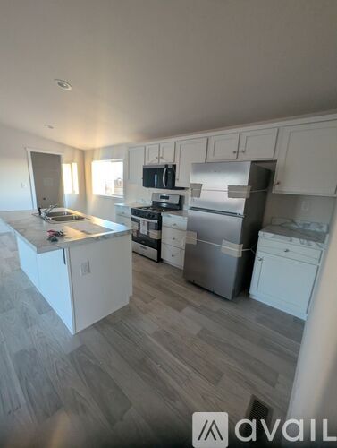 A kitchen with white cabinets and a wooden floor.