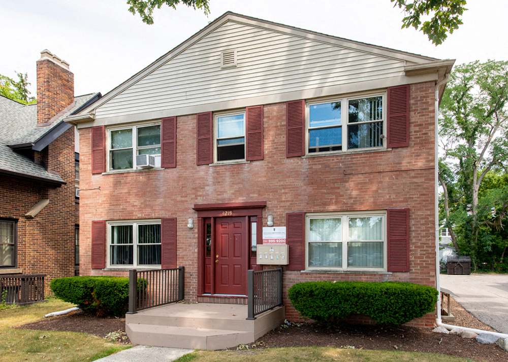 the front of a brick house with a red door