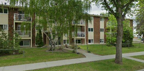 Apartment complex with a tree in front of it.