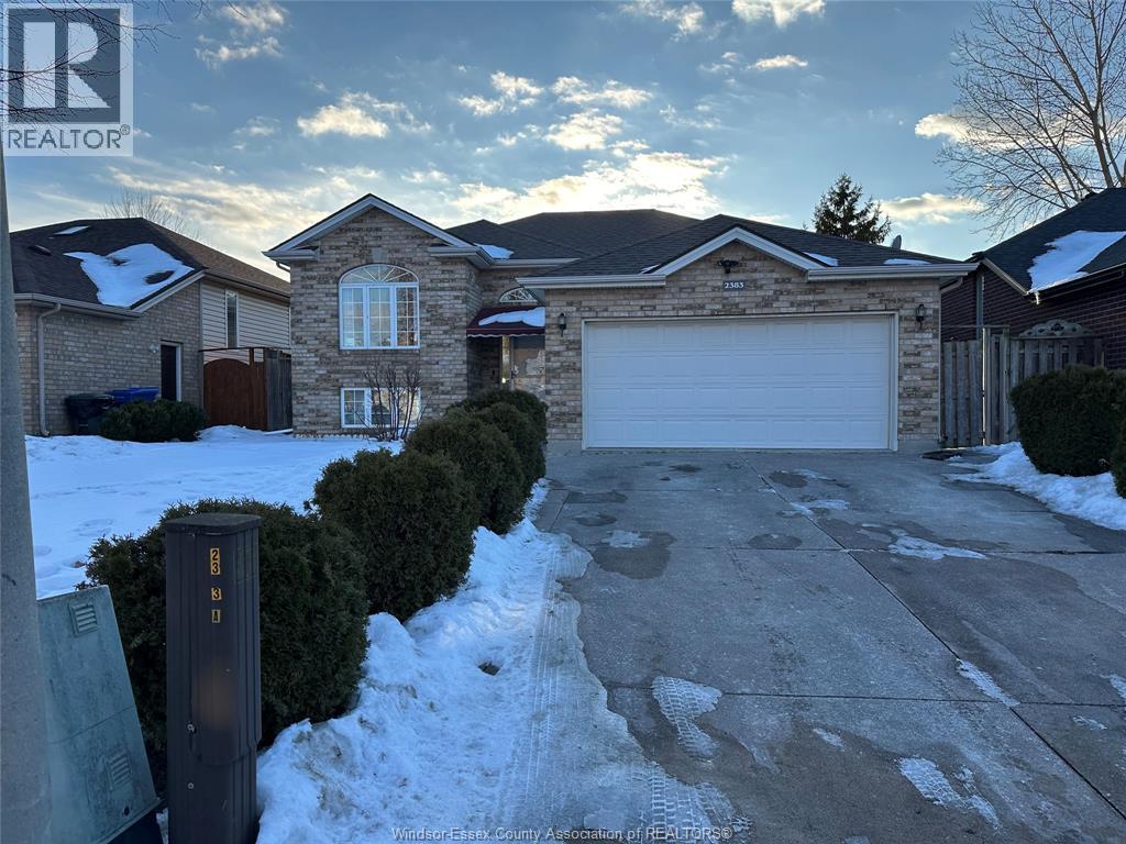 A house with a garage and a driveway in front of it.