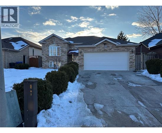 A house with a garage and a driveway in front of it.