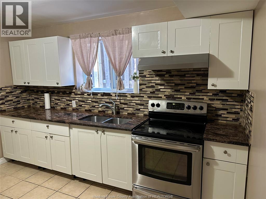 A kitchen with white cabinets and a stone backsplash.