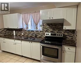 A kitchen with white cabinets and a stone backsplash.