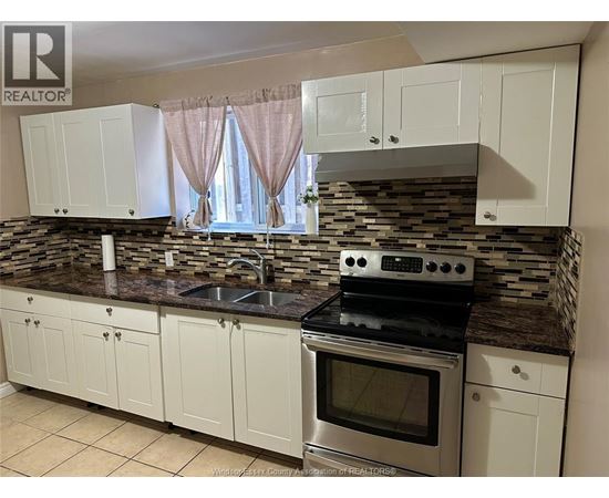 A kitchen with white cabinets and a stone backsplash.